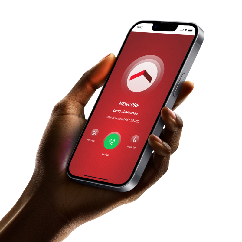 A mão esquerda de uma pessoa de pele negra segurando um smartphone. O smartphone mostra em sua tela o applicativo da Newcore, tocando um alerta que indica ao corretor a chegada de um novo lead.